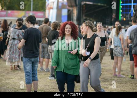 Sofia, Bulgarien — 25. Juni 2025. Zwei Frauen sprechen und spazieren durch die Menge während eines Rockkonzerts, umgeben von Festbesuchern, die die Outdoor-Sum genießen Stockfoto