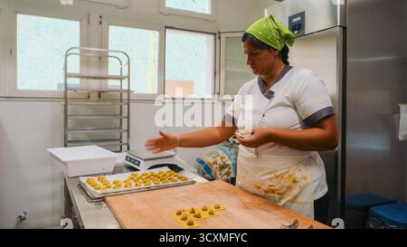 Piacenza, Italien - 1. Oktober 2025 fokussierte Handwerkerin fertigt fachmännisch kleine Kartoffelknödel von Hand in einer hellen kommerziellen Küche mit To Stockfoto