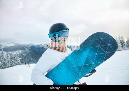 Porträt Der Frau Auf Dem Hintergrund Der Berge. Ein Snowboard halten und Skibrille tragen Stockfoto