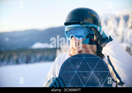 Porträt einer Frau, die ein Snowboard hält und Skibrille trägt. Stockfoto