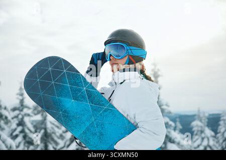 Skibrille Von Snowboardern Mit Dem Spiegelbild Der Verschneiten Berge. Wintersport. Porträt einer Frau, die ein Snowboard hält Stockfoto