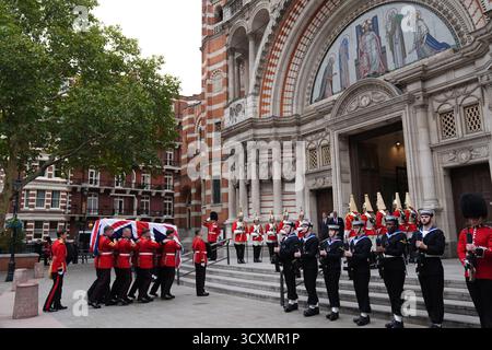 Tri-Service-Mitarbeiter der Royal Navy, der Royal Air Force und der Army säumen den Weg zur Kathedrale, während die Trägerpartei, bestehend aus Mitgliedern der Walisischen Garde, den Sarg, der mit einer Flagge von Union Jack versehen ist, zur Requiem-Messe für den ehemaligen Chef der Streitkräfte, Feldmarschall Lord Guthrie, in der Westminster Cathedral im Zentrum Londons trägt. Bilddatum: Mittwoch, 15. Oktober 2025. Stockfoto