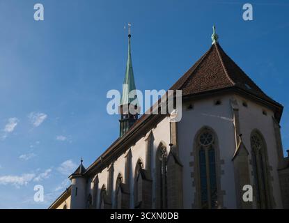 Historische französische Kirche in Bern, Schweiz – Dach und Turm des gotischen Gebäudes, das sich vor einem klaren blauen Himmel erhebt Stockfoto