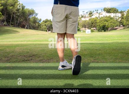 Rückansicht eines jungen Mannes, der auf dem Golfplatz Golf spielt. Stockfoto
