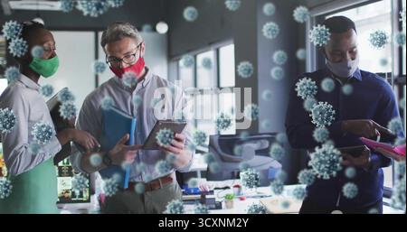 Kollegen, die im Büro Masken tragen, Tablets und Virenüberlagerungen tragen Stockfoto