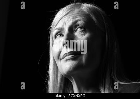 Ältere Frau weint auf dunklem Hintergrund, Tiefwinkelansicht. Schwarzweiß-Effekt Stockfoto