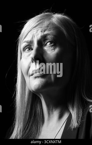 Ältere Frau weint auf dunklem Hintergrund. Schwarzweiß-Effekt Stockfoto