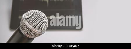 Nahaufnahme eines Mikrofons mit Schallwellenhintergrund auf grauer Oberfläche. Stockfoto