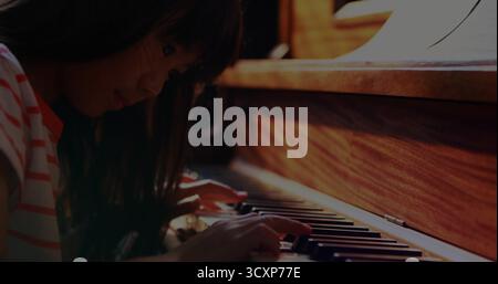 Chinesisches Mädchen, das Klavier spielt in der Ecke, mit Noten auf dem Stand, Kopierraum Stockfoto