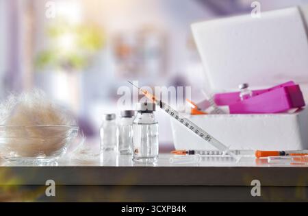 Detail eines Haustierallergie-Impfstoffsets mit einem Behälter und mehreren Dosen Flaschen und Spritzen auf einem weißen Tisch mit einer Schüssel voller Allergene und ein Leben Stockfoto