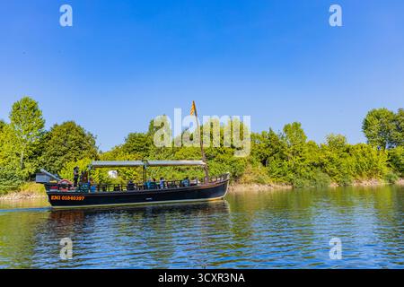 Beynac-et-Cazenac, Frankreich: 20. August 2024: Traditionelles Boot auf dem Fluss Dordogne mit dem Dorf Beynac-et-Cazenac im Hintergrund. Ort im Dorf Stockfoto