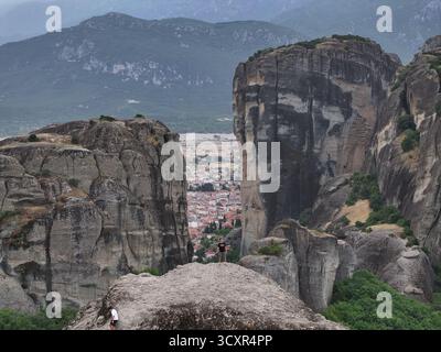 Die Besucher erkunden meteoras hoch aufragende Felssäulen mit Blick auf die traditionelle Stadt kalabaka im Tal darunter, mit dramatischen Klippen, Monaste Stockfoto