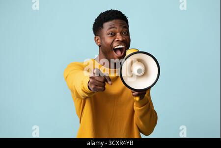 Emotionaler Afroamerikaner mit Megaphon, der Ansage macht Stockfoto