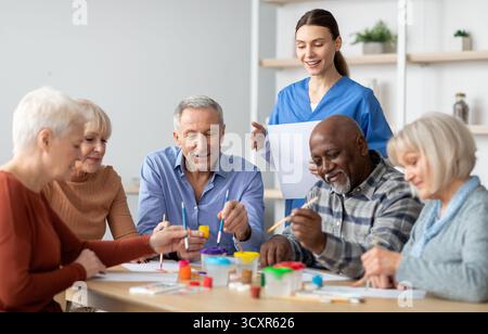 Glückliche ältere Männer und Frauen, die gemeinsam Kunsthandwerk machen Stockfoto