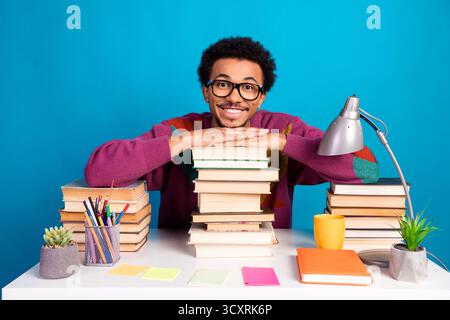 Fröhlicher Schüler, umgeben von organisierenden Werkzeugen und Büchern, symbolisiert akademischen Erfolg und kreative Motivation in einer hellen Umgebung Stockfoto