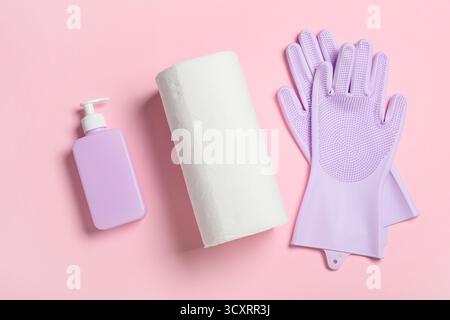 Papiertücher mit Gummihandschuhen und Flasche Seife auf rosa Hintergrund Stockfoto