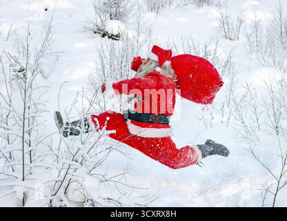Weihnachtsmann mit einem Sack, der in verschneite Natur läuft Stockfoto