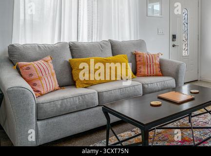 Graue Schlafcouch mit bunten Kissen und einem Couchtisch im Wohnzimmer Stockfoto