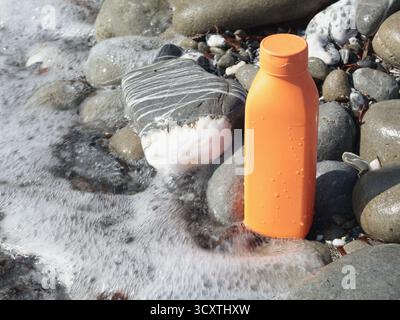 Roter Schönheitsbecher aus Plastik vor dem Hintergrund natürlicher Elemente. Kosmetik und Gesichts- und Haarpflege. Modellvorlage für die Konstruktion. Umweltfreundliche Produkte Stockfoto