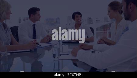 Führende Kollegen in Geschäftskleidung sitzen im Büro mit Notizbüchern und Stiften um einen Glastisch Stockfoto