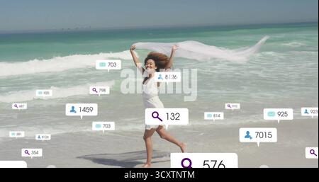 Eine Frau in weißem Sommerkleid, die einen Schal am Sandstrand hält, mit Suchnachrichten-Symbolen Stockfoto