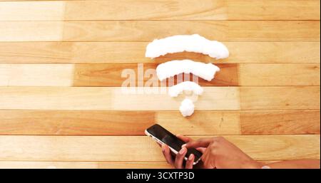 Berühren des Smartphone-Touchscreens mit männlicher Erwachsenenhand auf hölzerne Tischplatte, mit Schaum-Wi-Fi-Symbol Stockfoto