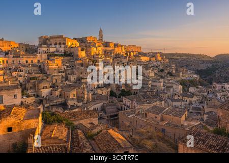 Ein Bild von einem ruhigen Blick auf Matera bei Sonnenaufgang, während die Sonne gerade über dem Horizont aufgeht. Die historischen Steinhäuser des Sassi di Matera leuchten auf Stockfoto