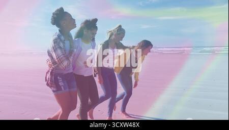 Gruppe von vier Freunden Arm in Arm am Strand in lässigen Denim-Outfits, Pastellhimmel Stockfoto