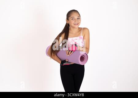 Mädchen in rosa Tanktop, schwarze Leggings, Yoga-Matte in der Hand Stockfoto