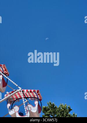 Ein helles Riesenrad, das sich gegen den blauen Himmel erhebt Stockfoto