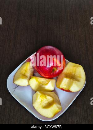 Eine Komposition aus ganzen und geschnittenen ​​apples, die auf einem Teller liegen, ist bereit, als gesunder und vitaminreicher Snack zu essen. Stockfoto