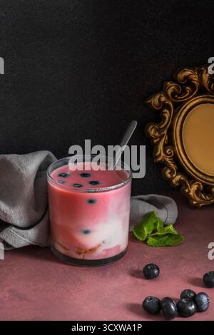 Stillleben mit wilden Heidelbeeren und einem Heidelbeeren- und Granatapfelsaft-Smoothie auf nordischer Birkenholzoberfläche Stockfoto