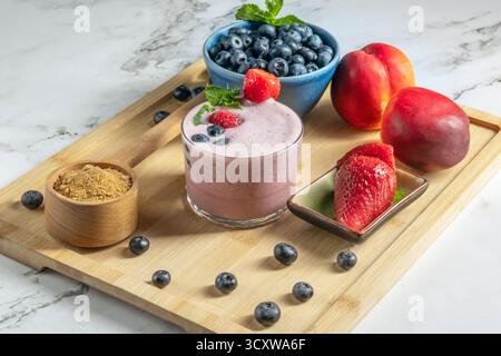 Komposition mit Heidelbeeren und einem Heidelbeeren-Marcona-Mandel-Smoothie auf Bambusholzoberfläche Stockfoto