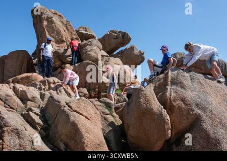 Touristen, die auf den Felsen klettern, Côte de Granit Rose (Rosa Granitküste), Ploumanac'h, Côtes-d'Armor, Bretagne, Frankreich, 2025 Stockfoto