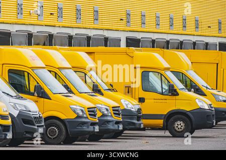 Reihen geparkter gelber Lieferwagen vor dem DHL Logistiklager Stockfoto