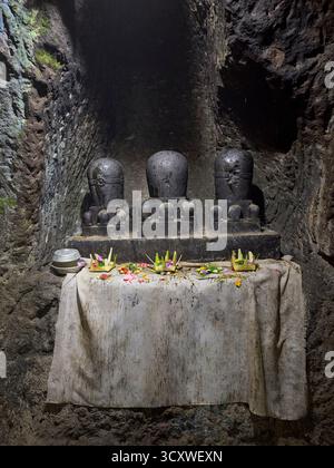 Traditionelle balinesische Opfergaben auf dem Altar an drei Steinlingams in der Elefantenhöhle in Goa Gajah, Hindutempel in Ubud, Gianyar, Bali, Indonesien. Stockfoto