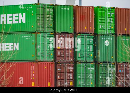 Stapel von Schiffscontainern in einem belebten Flusshafen am Rhein in Düsseldorf Stockfoto