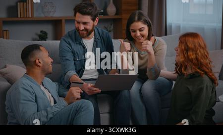 Fröhlich glücklich Multiracial vier Freunde Shopping Laptop feiern Applaus Ja Geste erfolgreiches Gewinnspiel Online-Wetten Casino zu Hause Stockfoto