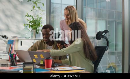 Drei multiethnische Kollegen aus dem Business Team arbeiten in informellen kreativen Startup Talk zusammen, um Daten im Cyberspace für digitale Tablet-Notebooks zu analysieren Stockfoto