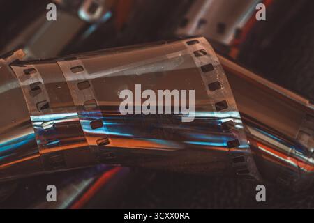 Nahaufnahme eines gerollten 35-mm-Filmstreifens mit filmischem Leuchten und Lichtreflexionen. Konzept von Film, Filmstreifen, Retro-Kino, analoger Fotografie Stockfoto