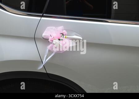 Rosafarbene und weiße Blumendekoration am Autogriff symbolisiert die Feier Stockfoto