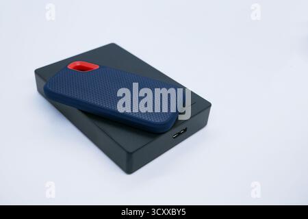 Nahaufnahme von zwei externen Festplatten – einem kompakten SSD und einer größeren Festplatte – auf weißem Hintergrund. Technologie-, Daten-, Backup- und Hardwarekonzepte. Stockfoto