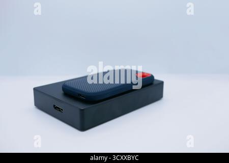 Nahaufnahme von zwei externen Festplatten – einem kompakten SSD und einer größeren Festplatte – auf weißem Hintergrund. Technologie-, Daten-, Backup- und Hardwarekonzepte. Stockfoto