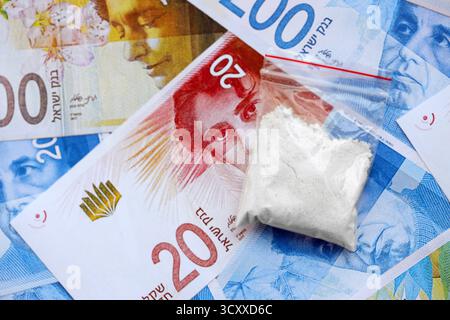 Israel New Shekels Banknoten und Kokain Pack. Die aktuellen israelischen Geldrechnungen und Suchtstoffe liegen in großer Menge auf dem Tisch. Das Konzept des Drogenhandels in Israel Stockfoto