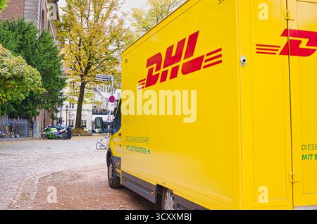 Gelber DHL-Lieferwagen auf der europäischen Straße mit Herbstbäumen und Fahrrädern in der Nähe Stockfoto
