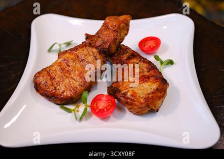 Gegrillte Schweinefleisch-Steaks, Schweinehals mit Kräutern und Gewürzen auf der Grillpfanne, Restaurantmenü, Diät, Kochbuchrezept für Text. Hochwertige Fotos Stockfoto