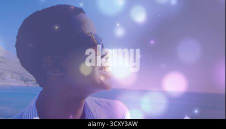 Stehende Frau mit Sonnenbrille und gestreiftem Hemd, die auf das ruhige Meer auf die Klippe blickt, Kopierraum Stockfoto