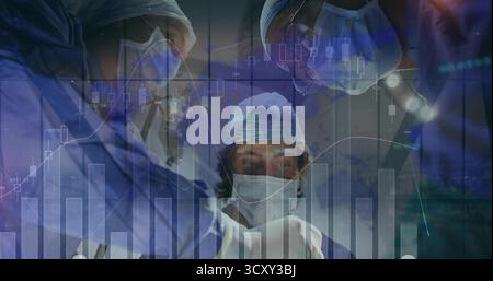 Sie sammeln maskierte Chirurgen, die Schutt tragen und in ODER unter Licht operieren, mit Überlagerungen in Finanzdiagrammen Stockfoto