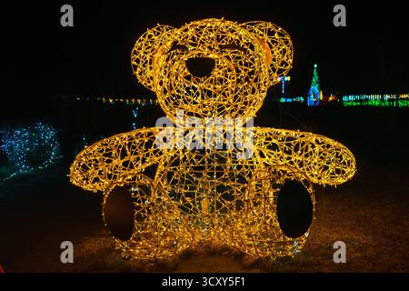 Riesige beleuchtete goldene Lichtinstallation. Weihnachtsschmuck in Bärenform mit dekorativen Lichtern, die nachts im Outdoor-Park hell leuchten. A Stockfoto