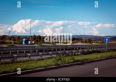Ein Parkplatz in der Nähe einer Autobahn mit einer blauen tragbaren Toilette und mehreren Straßenlaternen. Stockfoto